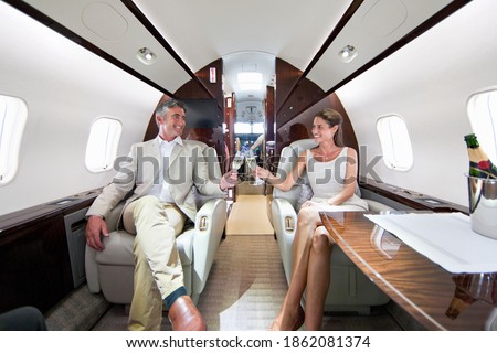 Close up of a smiling couple making a toast with champagne glasses in a private jet Royalty-Free Stock Photo #1862081374