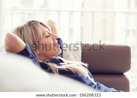 Relaxed young woman lying on couch Royalty-Free Stock Photo #186208322