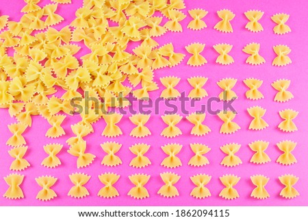farfalle arranged in columns on a bright pink background. Pasta pattern.
