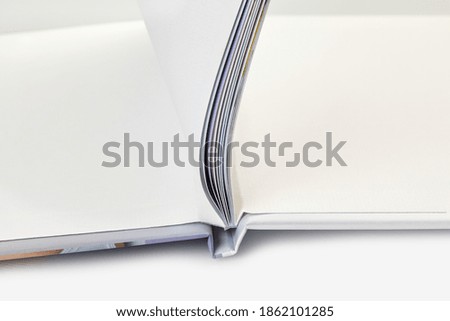 Open photo book with hardback and blank pages on white studio background. Close up, copy space