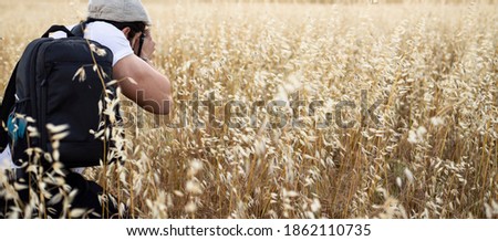 male photographer takes pictures in the barley