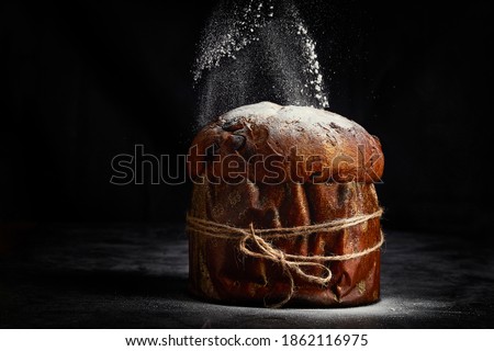 
Easter bread. Christmas panettone. Glass sugar falls dusted on the panettone on a dark background.