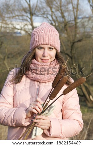 A girl in autumn clothes with a bouquet of reeds in her hands. Walking in nature in the park. Close-up shot.