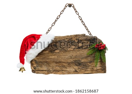 Christmas template - old wooden sign with Santa hat and spruce twig hanging on a rusty chain on white background