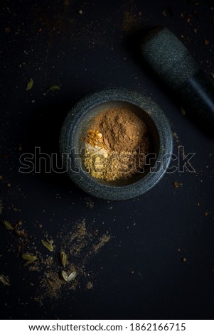 Spices in mortar with pestle on dark background