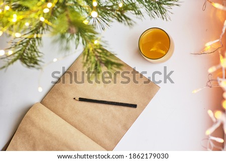 Flat lay, top view home table desk. Workspace with blank clip board, pencil, green pine with spark, and orange juice glass on white background.