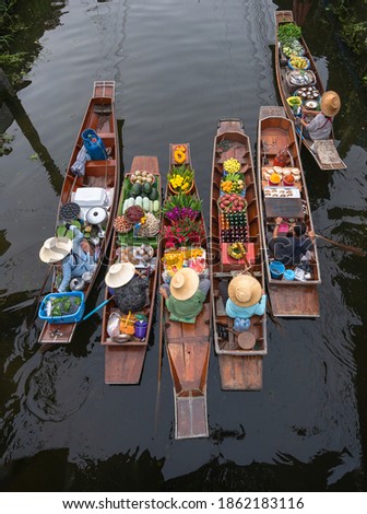 Peoples sell agriculture fruit and food on wooden boat at Damnoen Saduak Floating Market is popular tourist attraction on canals of Thailand. Royalty-Free Stock Photo #1862183116