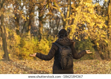 
Woman with her arms outstreched enjoys in autumn as she walks through the park