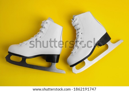 Pair of figure ice skates on yellow background, flat lay