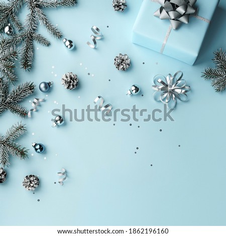 Merry Christmas card made of gift boxes, blue, white, silver decorations, bows, fir branches, sparkles and confetti on blue background. Xmas and New Year holiday, bokeh, light. Flat lay, top view