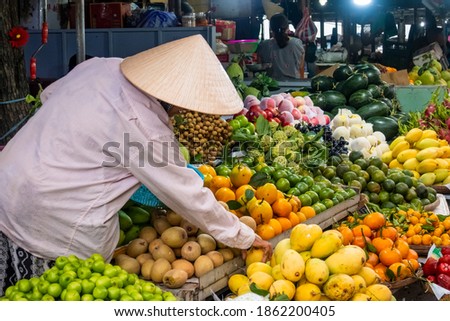 Vendor at his fruit and vegetable stall at a market in Hoi An, Vietnam.