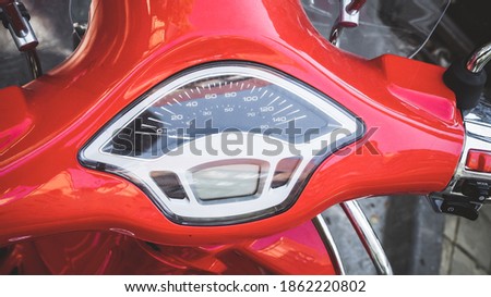 Speedometer on the handlebar of a glossy red motorcycle. Closeup photo