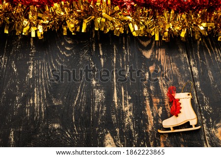 christmas flat lay with place for text, red and golden tinsel and wooden skates lying on a dark wood table