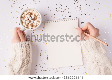 Top above overhead close up view photo of female hands using wooden pen writing text to the open blank sketch book drinking tasty beverage