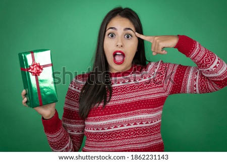 Young beautiful girl holding gift over isolated white background smiling and thinking with her fingers on her head that she has an idea.