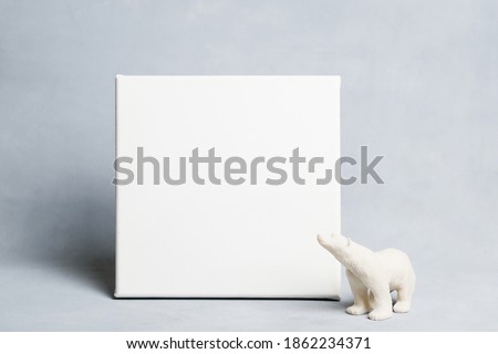 White empty canvas board and toy polar bear on gray background. Mockup poster frame.