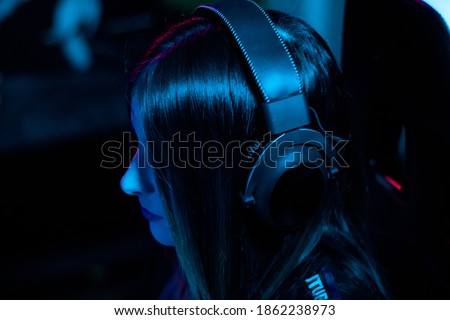 Close up shot of a individual gamer girl with the helmets on while she is sitting blue lights
