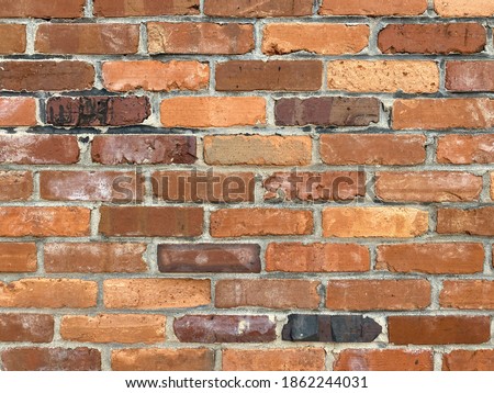 colorful red brown tan vintage old brick wall with dirty grudge cement grout and deep shadows highlighting the retro look and feel of a warehouse building alley wall perhaps in a small rural town