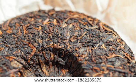 Chinese extruded aged pancake-shaped Puer tea high quality with red tea buds, macro picture with blurred background. 