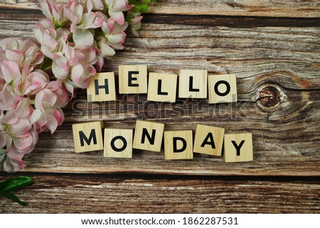 Hello Monday alphabet letter with Blooming flower on wooden background