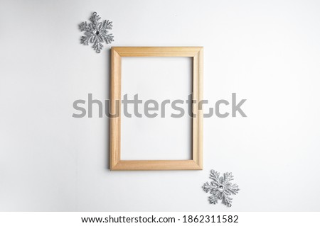 Mockup wooden frame and decorative snowflakes on a white background. An idea for your Christmas and holiday photos. Holiday text in a frame