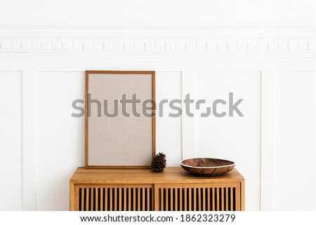 Blank large frame on a wooden sideboard in a living room