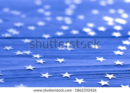 Festive creative background with bright confetti in the form of stars on a blue background. Selective focus. Copy space.