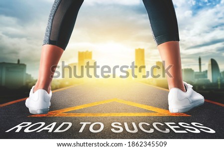 Woman runner leg standing on a success arrow sign to a modern light city skyline for business success pathway concept.