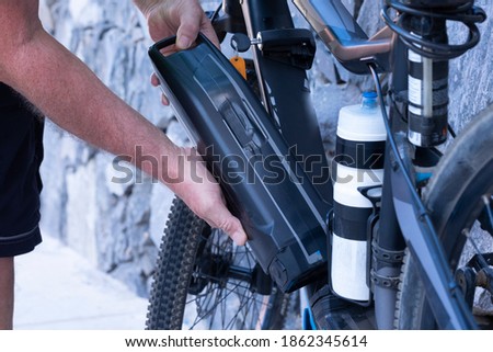 Hands of a man inserting the battery to the electric bike. Healthy lifestyle