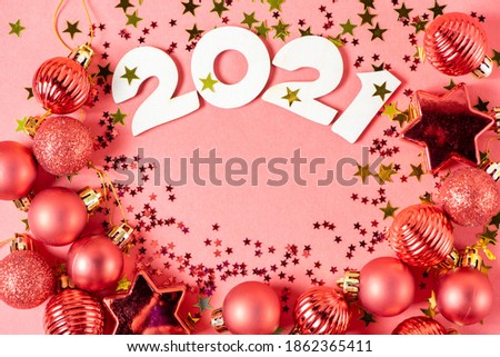 Wooden numbers 2021 on a paper background with shiny red Christmas balls, golden glitter stars close-up. Beautiful new year card