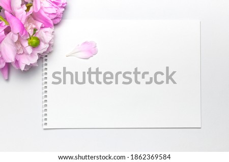 Blank clean white notepad album, beautiful pink peonies flowers on gray background. Top view flat lay copy space. Female desktop, woman working desk, breakfast, time for planning
