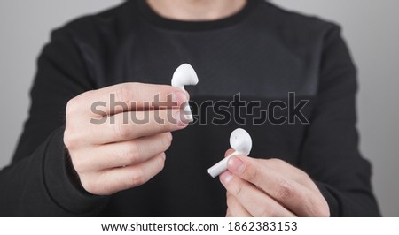 Caucasian man holding white wireless earphones.