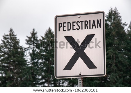 Close up of Pedestrian crossing sign on the road with forest in the background in Courtenay, Canada