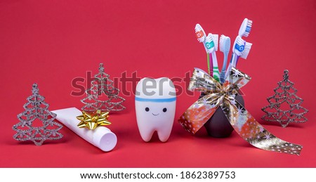 tooth model, toothbrushes in a vase with a gift ribbon and toothpaste on a red background