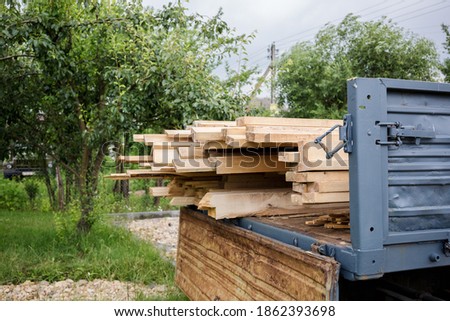 A planed board lies on board the truck. Building materials were brought to the construction site. Chopped wood for interior use. Cargo transportation of oversized items. Banner with copy space.