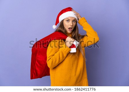 Lithianian woman with christmas hat isolated on purple background with surprise expression