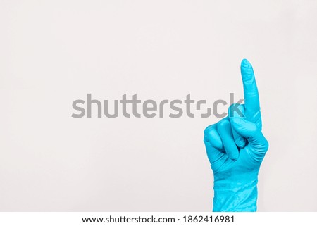 The doctor's hand in a blue glove shows the index finger on a white background with space for text. Banner for medical clinic, photo for medicine and pharmacy