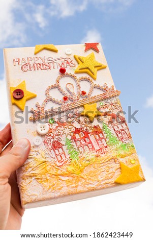 box lid decorated with Christmas scenery. Collage of houses and crumpled paper. Craft with textures.