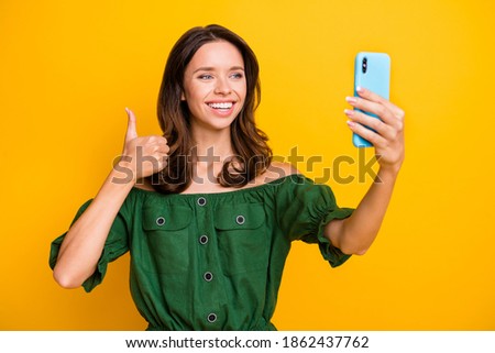 Photo of attractive young woman wear green off-shoulders blouse make thumb up take selfie isolated on yellow color background