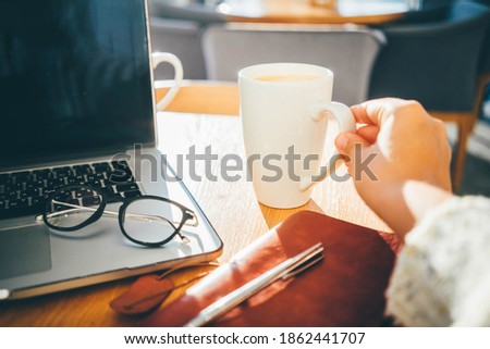  Woman using a laptop during a coffee break, hands close up