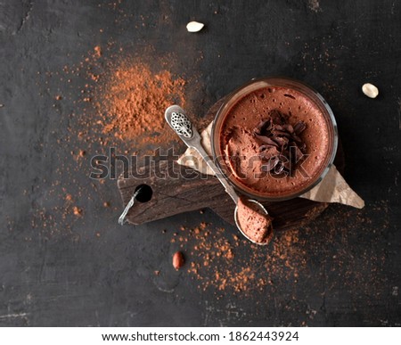 Vegan chocolate mousse glass on a wooden board with a spoon on a dark background. Top view. Flat lay Royalty-Free Stock Photo #1862443924
