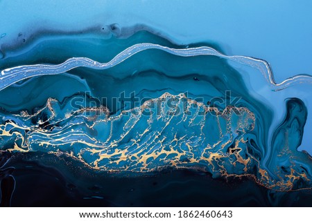 Acrylic Fluid Art. Golden wave in abstract ocean of blue paint and gold powder particles. Marble effect background or texture.