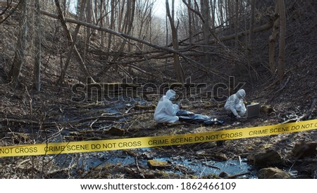 Detectives are collecting evidence in a crime scene. Forensic specialists are making expertise. Police investigation in a forest. Royalty-Free Stock Photo #1862466109