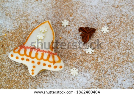Christmas composition: cookie decorated in the shape of a bell on a wooden background and powdered sugar