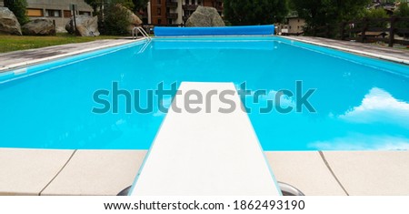 Diving board and an empty swimming pool, with reflections in the water Royalty-Free Stock Photo #1862493190