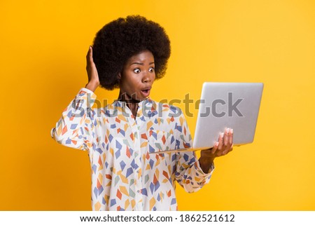 Photo of shocked dark skin woman wear casual outfit looking holding modern device arm head isolated yellow color background