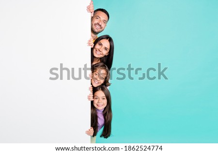 Photo portrait of full family with small children peaking from the side of white banner poster isolated on vivid turquoise colored background