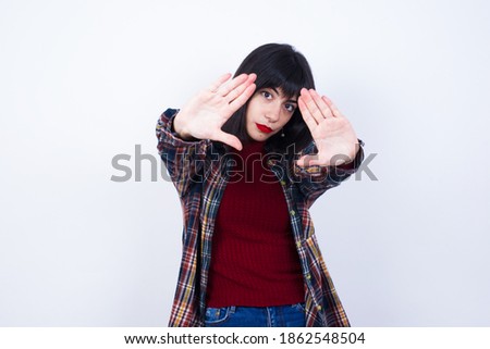 Portrait of smiling MODEL looking at camera and gesturing finger frame. Creativity and photography concept.