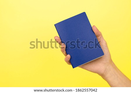 Blank blue card in a female hand on a yellow background