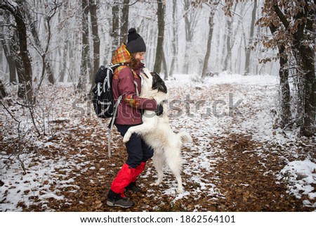 woman with dog walking in frost covered forest in winte